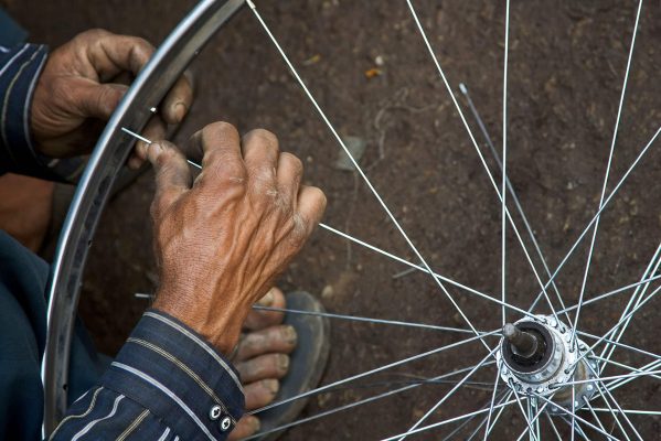 Two hands fixing a Bicycle wheel, Varanasi Benares India